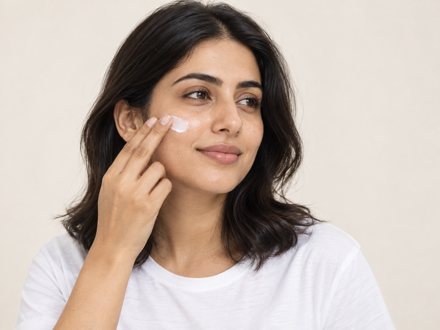 Woman applying sunscreen to her cheek